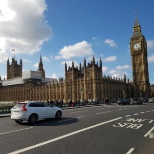 View of Big Ben and the Palace of Westminster with traffic and pedestrians on a sunny day in London.