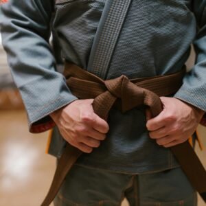 Close-up of a martial artist tying a brown belt, highlighting discipline and skill in combat sports.