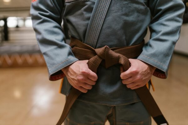 Close-up of a martial artist tying a brown belt, highlighting discipline and skill in combat sports.